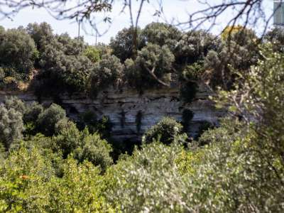 ...circondato da alte pareti rocciose nelle quali si intravedono le entrate di alcune grotte